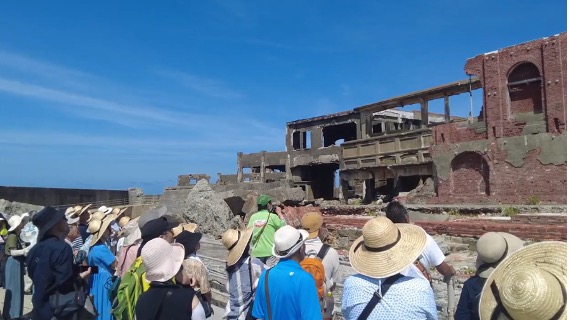 【写真5】島の指定見学広場で、ガイドの説明に耳を傾けるツアー参加者<br />